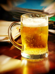 Lunch break-time.Beer glass on table with notebooks.Soft bokeh.