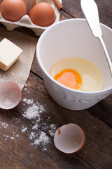 Ingredients and tools ready to make a cake, flour, eggs, butter, cinnamon stick on a wooden table.