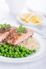 Baked salmon with rice, green peas and basil on a white ceramic plate on a white background.