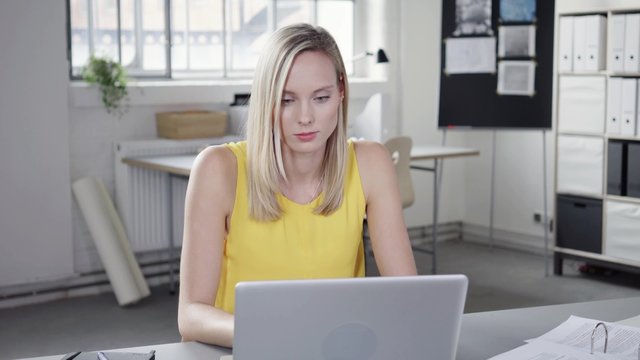 geschäftsfrau sitzt am schreibtisch und arbeitet am laptop
