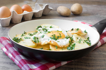 Potatoes, fried eggs and parsley in a frying pan