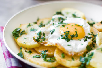 Potatoes, fried eggs and parsley in a frying pan