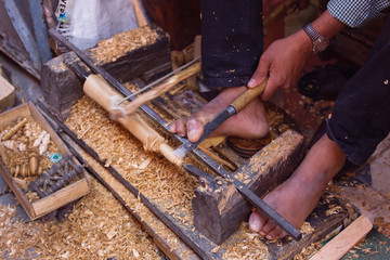 Man working the wood with his feet in Marrakech, Morocco