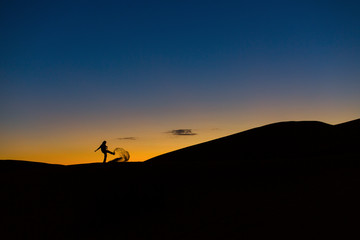 Man playing with sands in desert at sunset