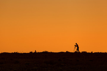 Fototapeta na wymiar Silhouette of photographer during sunset with tripod