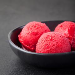 Cherry, raspberry, strawberry, cranberry , red sorbet,scoop, black stone background. 