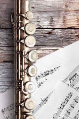 Old flute with sheet music on rusty wooden boards