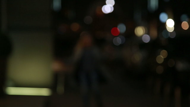 Young beautiful girl runs away from the camera in a blur on the night street