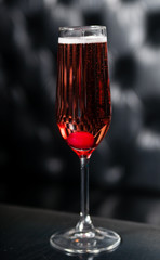 Glass of red sparkling wine served on a black table, ready for consumption