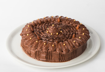 Homemade cake with black chocolate served on a white plate. Studio shot on white background
