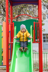 Happy boy sliding down on playground