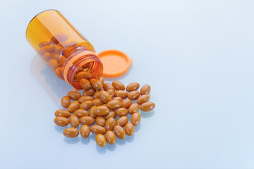 clear orange bottle and Capsules of oil spilled