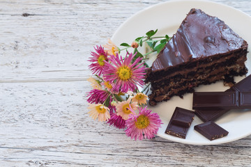 piece of chocolate cake on a plate with chrysanthemum flowers an
