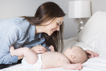 mother with baby on bed having fun