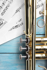 Trumpet with sheet music on blue wooden boards