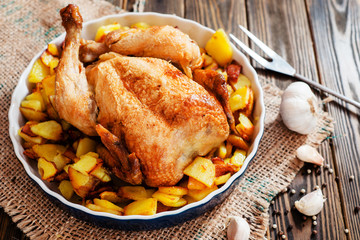 
Baked chicken with baked potatoes , apples , garlic and spices on a wooden background