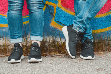 Black sneakers on couple's legs on the graffiti background