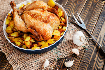
Baked chicken with baked potatoes , apples , garlic and spices on a wooden background