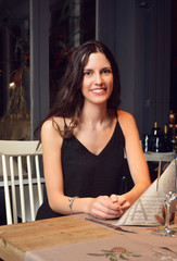 woman having dinner at a romantic restaurant and toasting with c