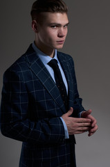 Seductive young man in a suit posing on gray background