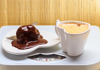 Coffee and chocolate cake on weighing scale.