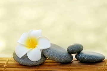 Fototapeta na wymiar Composition of pebbles and fragipani flower on wattled background