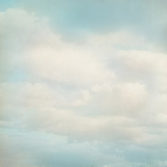 Old paper background with blue sky and white clouds in grunge style. 
