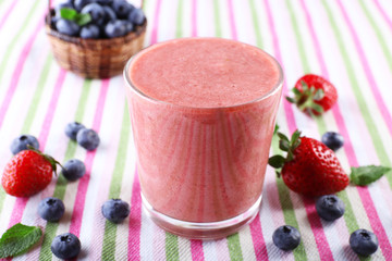 A glass of fresh cold smoothie with berries, on lined tablecloth background