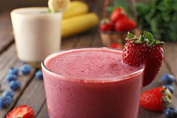 Glasses of fresh cold smoothie with fruit and berries, on wooden background, close-up