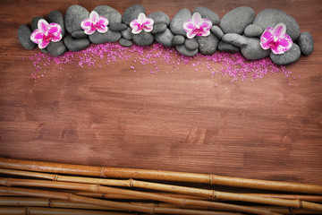 Spa stones and orchids on wooden background