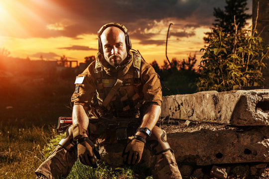American soldier with the M4 rifle is having a rest. Sunset on t
