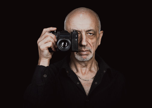 Senior man with old film camera in the dark