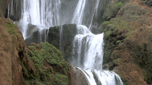 Closeup cascade of waterfalls on mountain stream flowing among stones in Morocco