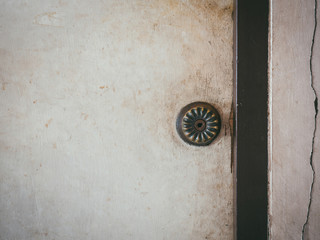 Doorknob on old wooden door and cracked wall