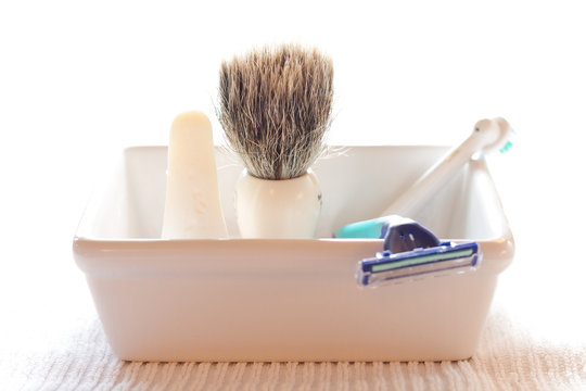Shaving brush and razor in soap dish, back lit.