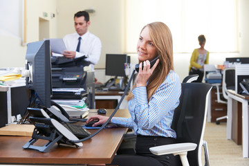 Fototapeta na wymiar Businesswoman Taking Phone Call In Busy Office