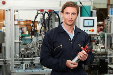 Portrait Of Engineer Holding Component In Factory