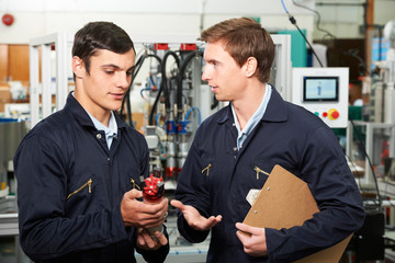 Engineer And Apprentice Discussing Component In Factory