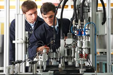 Engineer And Trainee Working On Equipment In Factory