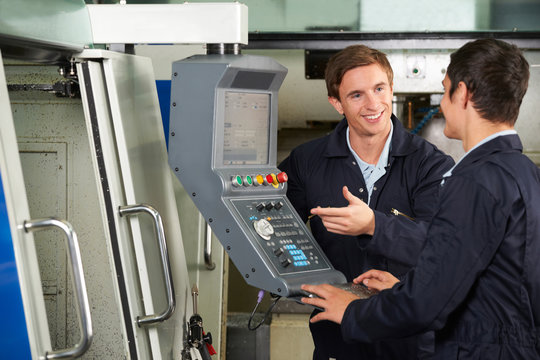 Engineer Instructing Trainee On Use Of Computerized Cutting Mach