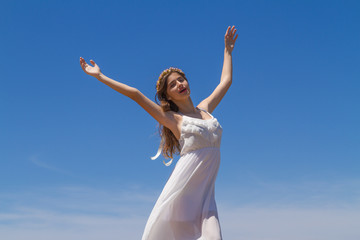 Fototapeta na wymiar Young brunette in white flimsy dress enjoys the summer sun.