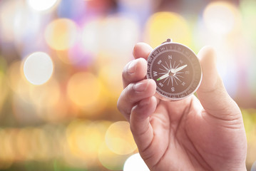compass in hand on defocused abstract bokeh lights christmas bac