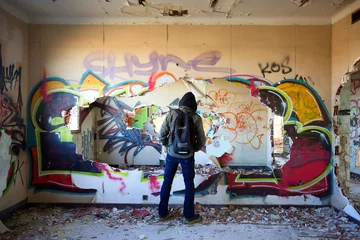 Papier Peint photo Graffiti Un homme de dos au dans un bâtiment rempli de graffitis