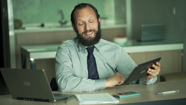 Friendly businessman with tablet talking good news in office
