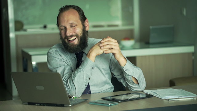 Happy businessman talking good news to camera in office
