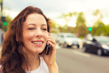 Happy young lady talking on mobile phone walking on a street