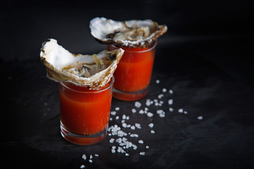 Oysters and bloody mary cocktail on black background