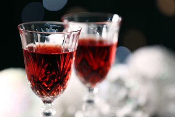 Wine glasses with Christmas decorations on snowy table, close up