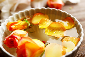 Beautiful orange rose and petals in a bowl of water, close-up