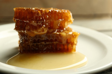 Honeycombs on plate on wooden background